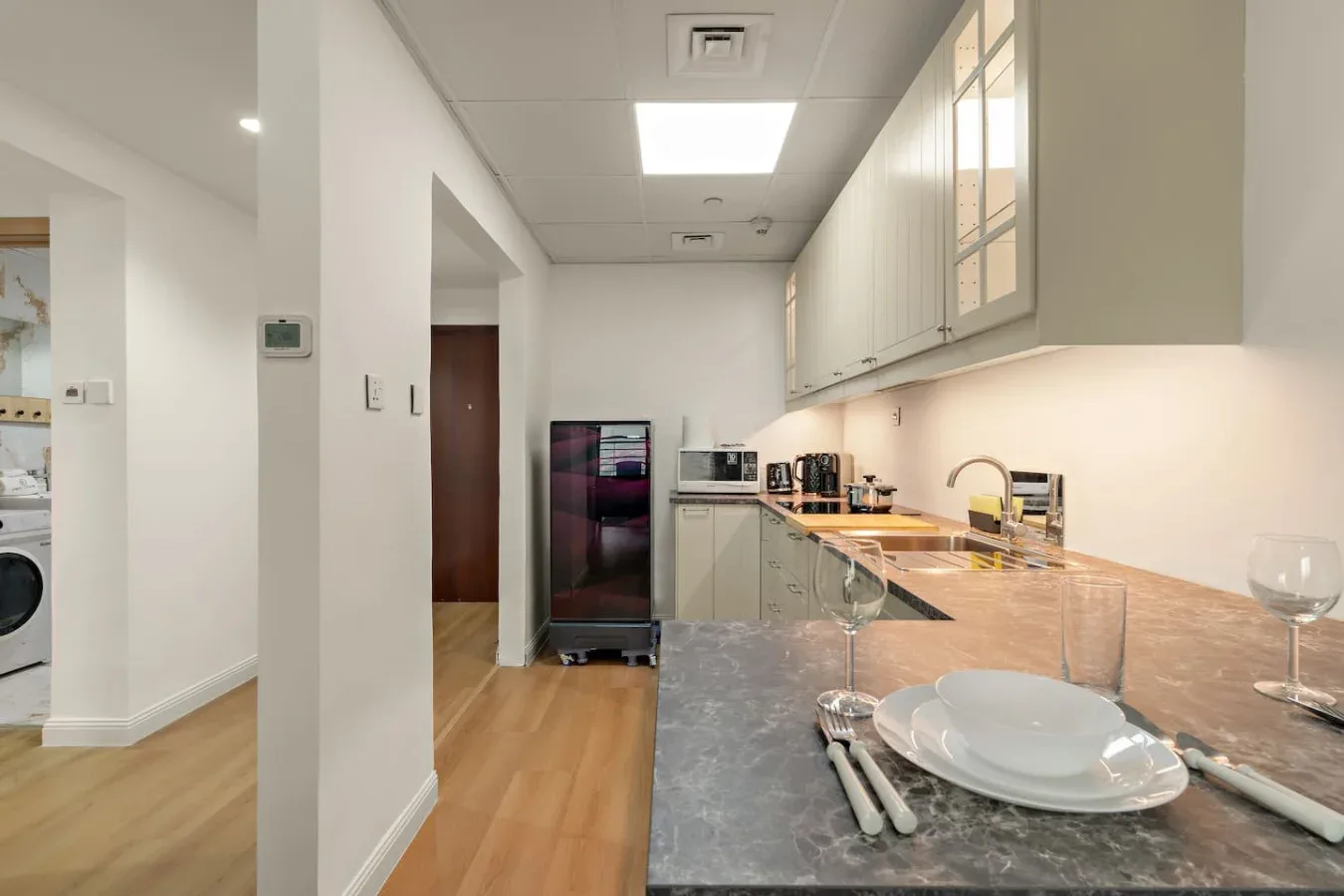 Una cocina luminosa con una encimera larga, armarios y electrodomésticos.