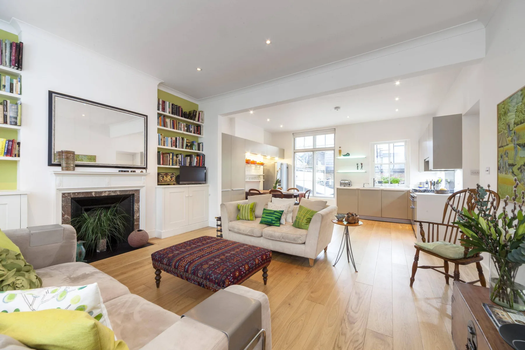 A bright living room opens into a kitchen, with sofas and a patterned coffee table.