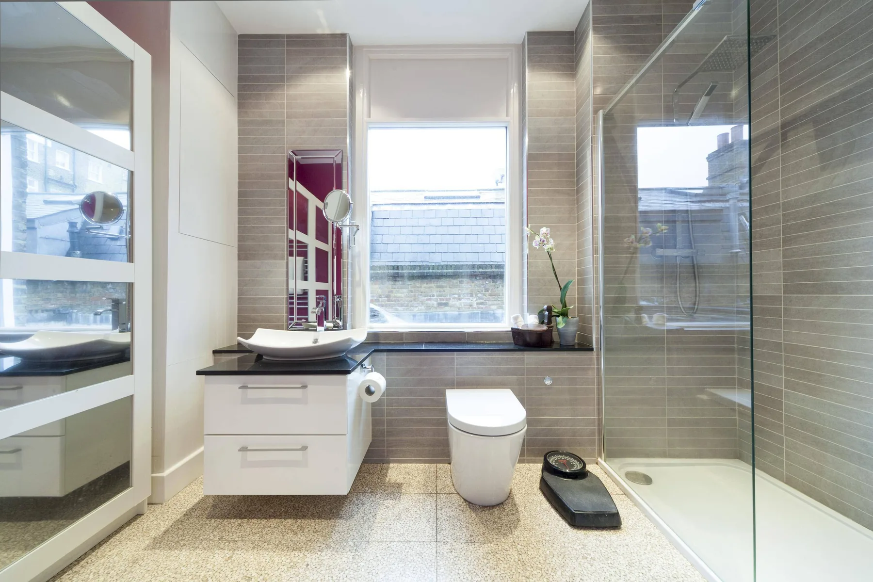 A bright bathroom with a vanity, toilet, and glass shower.