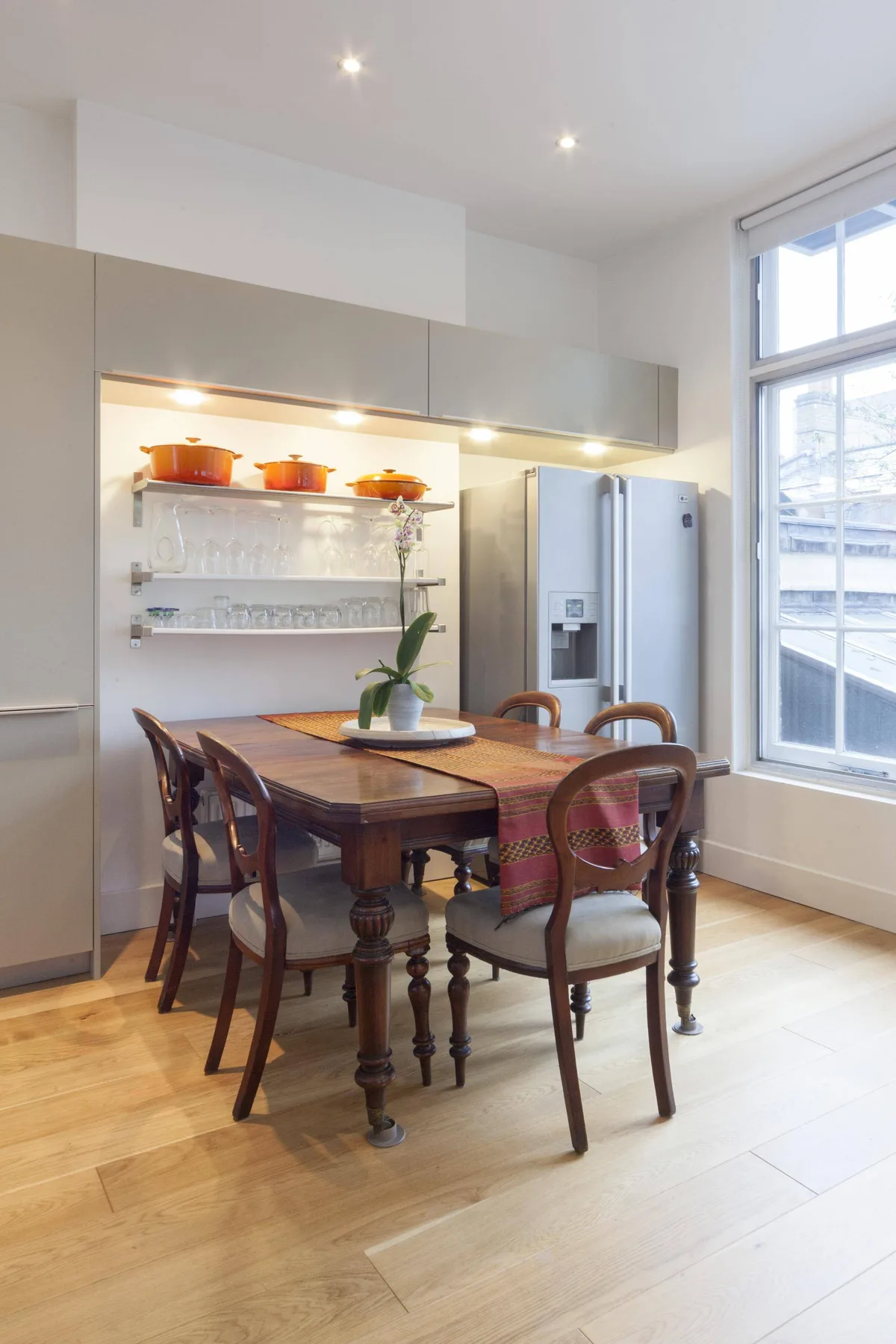 A dining area with a wooden table and chairs beside a large window.