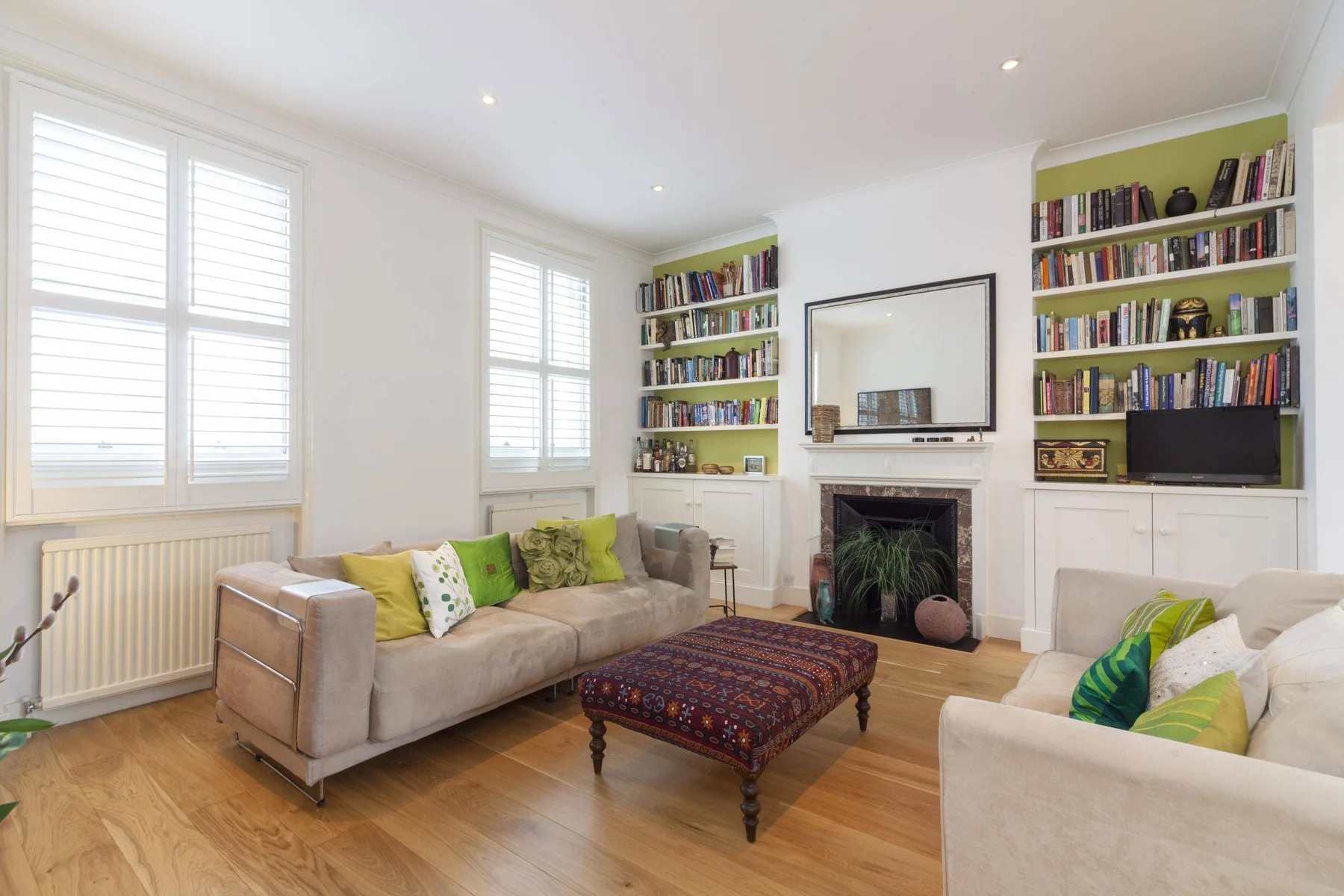 A bright living room with seating, bookshelves, and a fireplace.