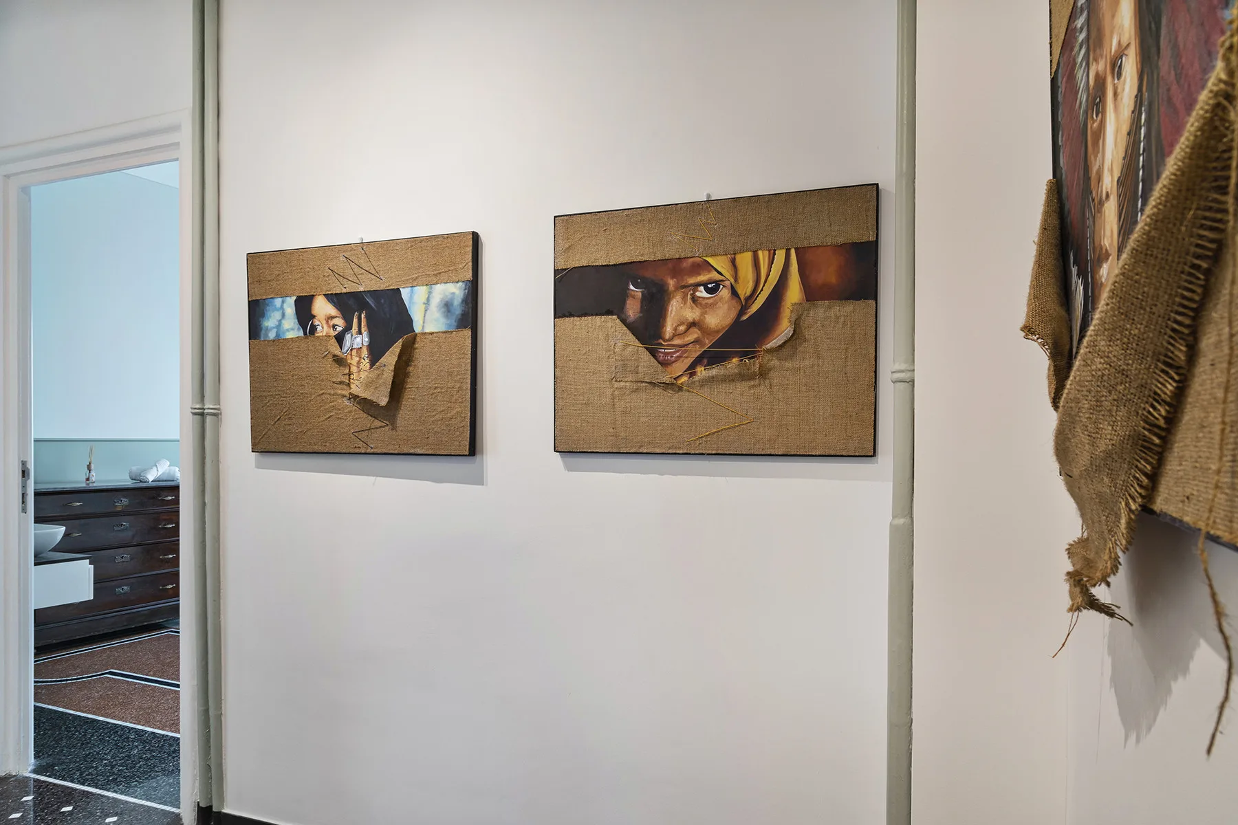 A hallway wall displays two framed artworks beside an open doorway.