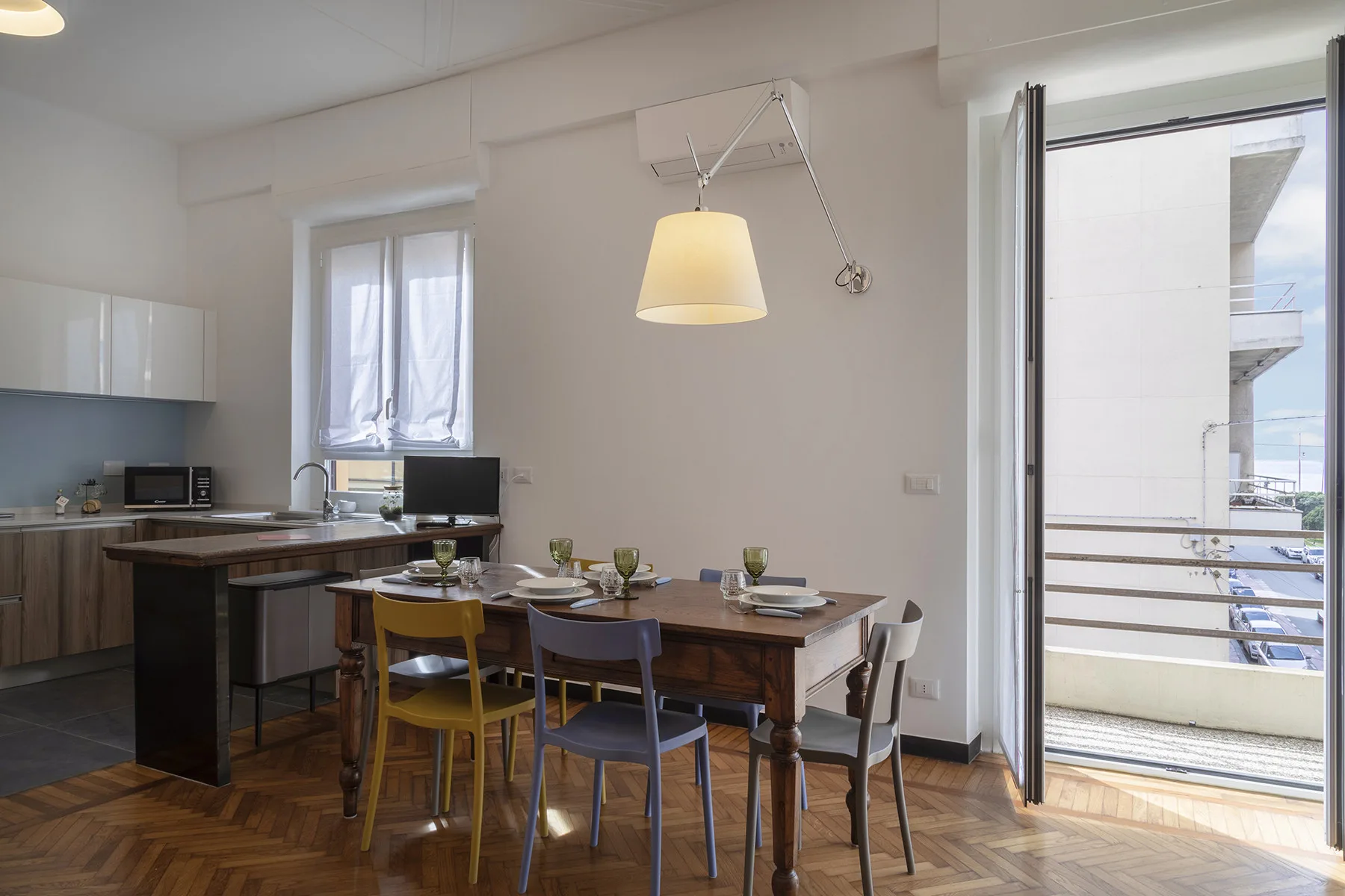 A dining area with a wooden table and chairs beside an open balcony door.