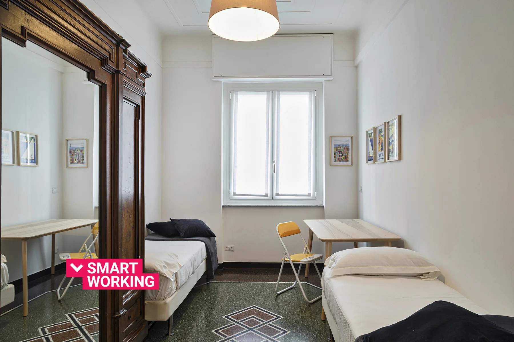 A bright bedroom with two beds, a window, and a small table.
