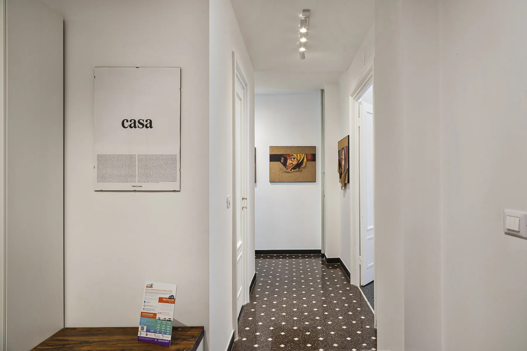 A bright hallway with framed artwork and a patterned carpet.