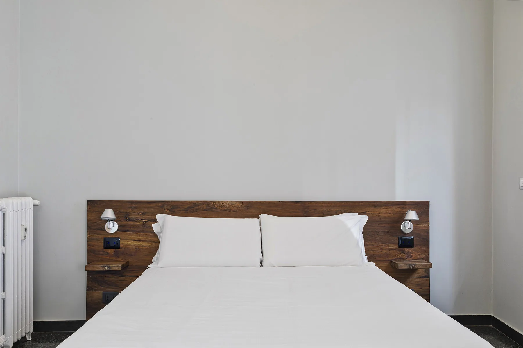A bedroom with a neatly made bed and a wooden headboard.