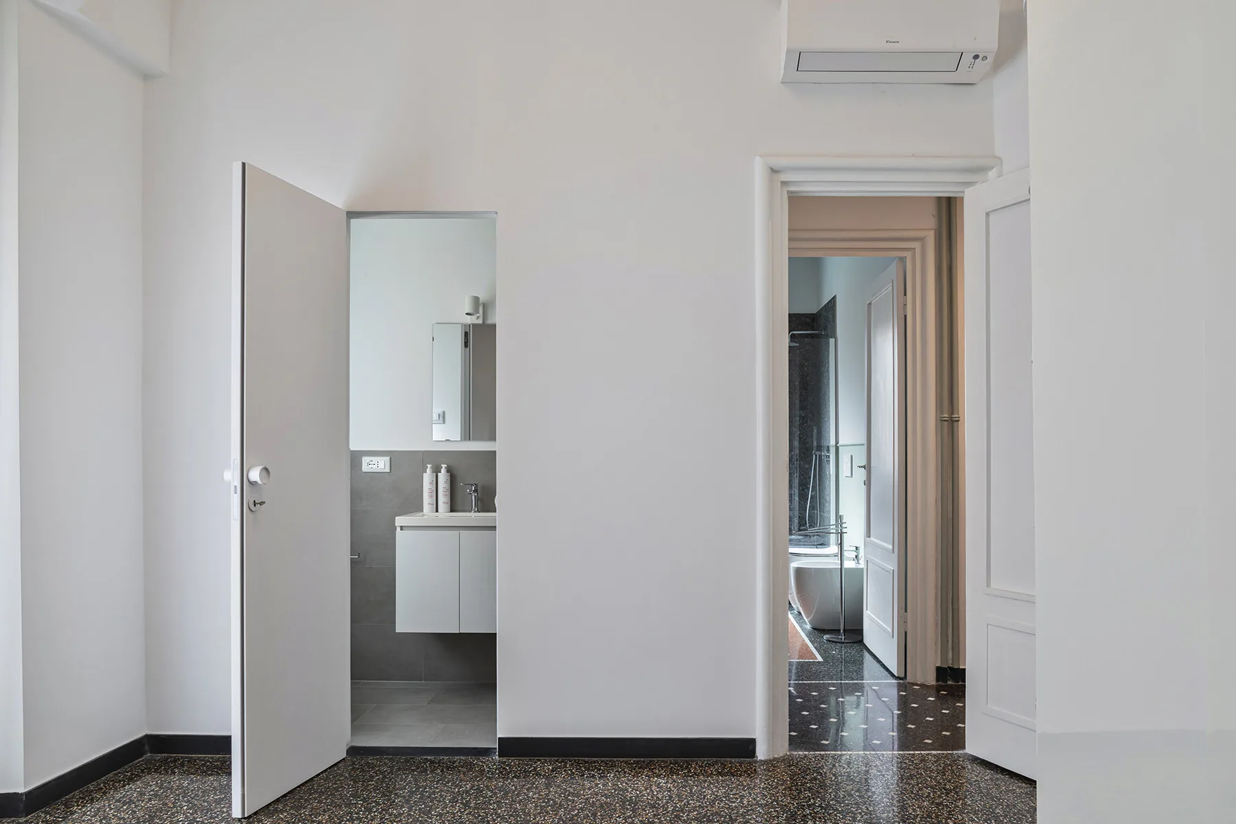 A bright interior hallway with an open bathroom doorway and a wall-mounted air conditioner.