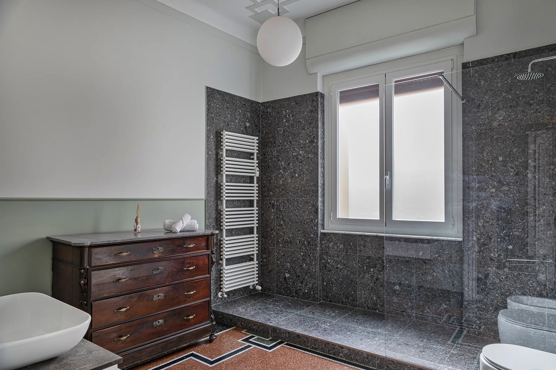 A bathroom with a bathtub, a towel radiator, and a window beside the shower.