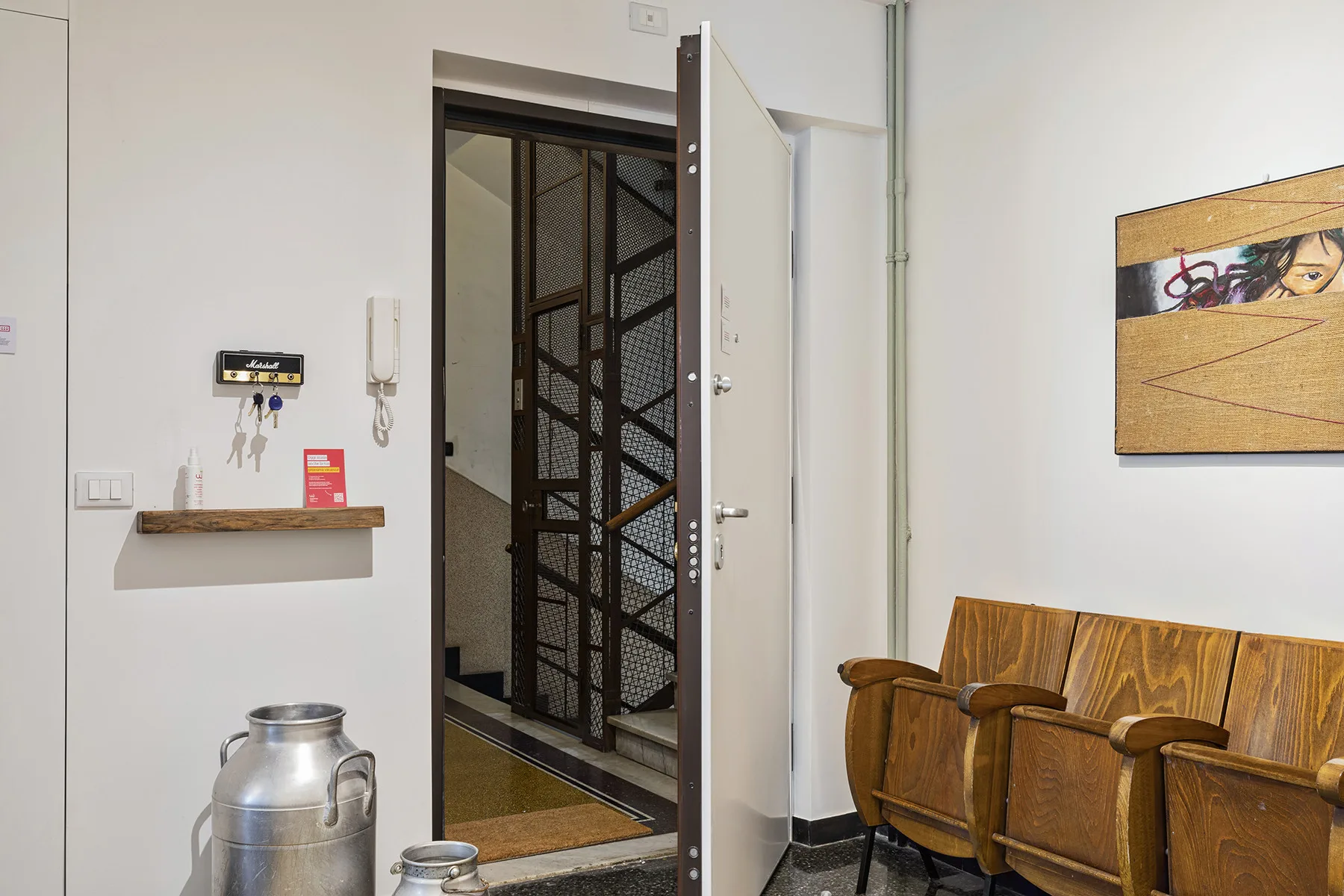 An entryway with an open door, a wall shelf, and wooden seating.
