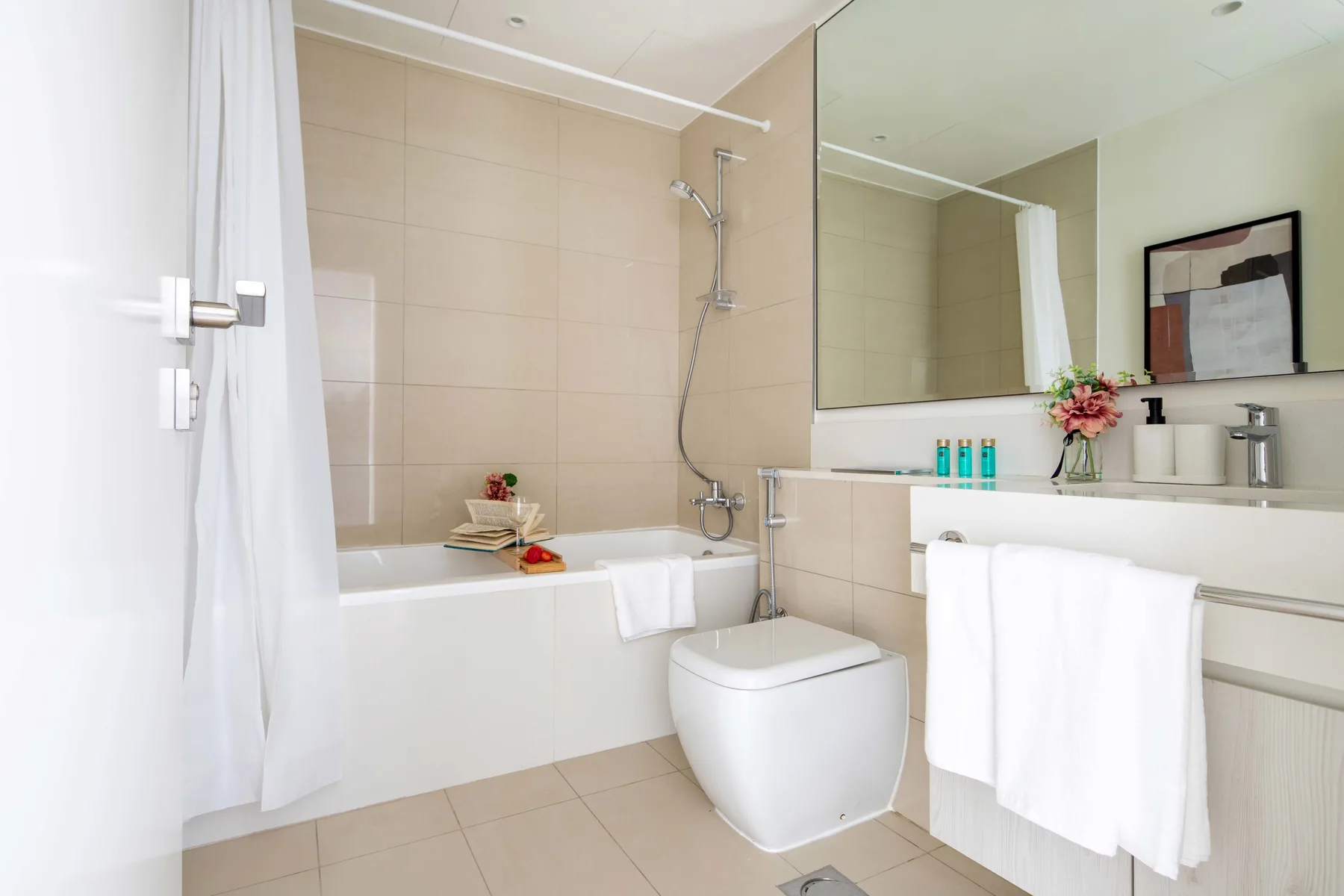 Un baño luminoso con azulejos, bañera, ducha y lavabo.
