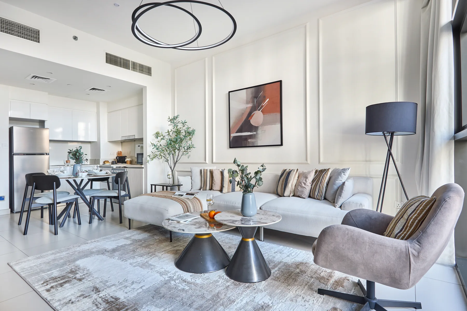 Una sala luminosa con un sofá, un sillón y una mesa de centro redonda.