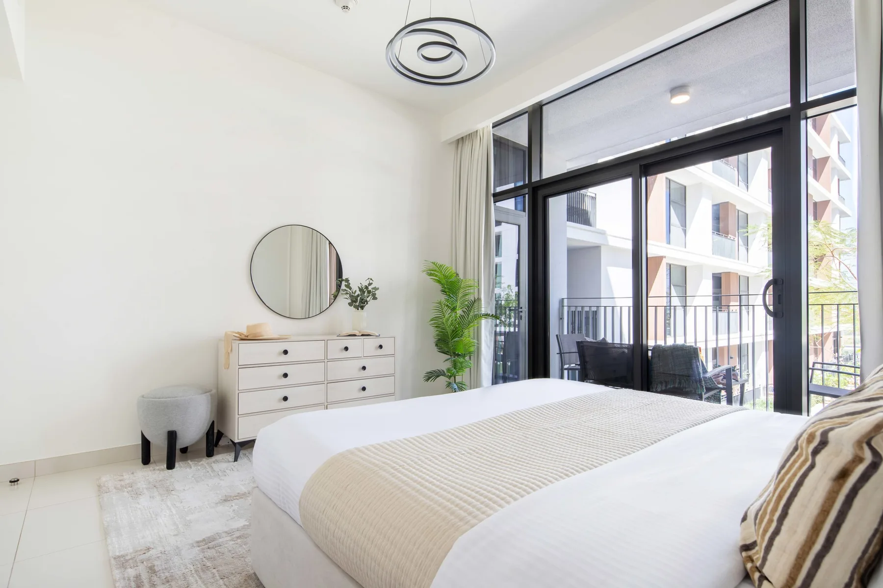 Un dormitorio luminoso con una cama tendida y grandes puertas de vidrio.