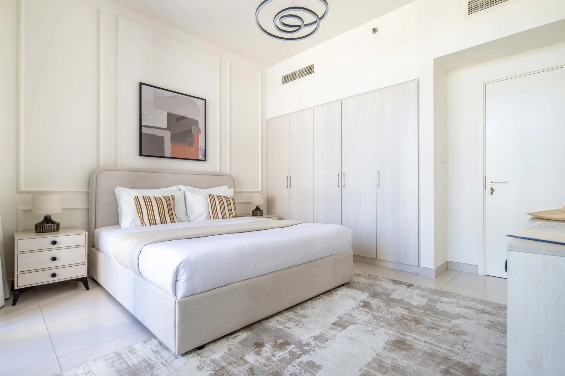 Un dormitorio luminoso con una cama bien hecha y armarios empotrados.
