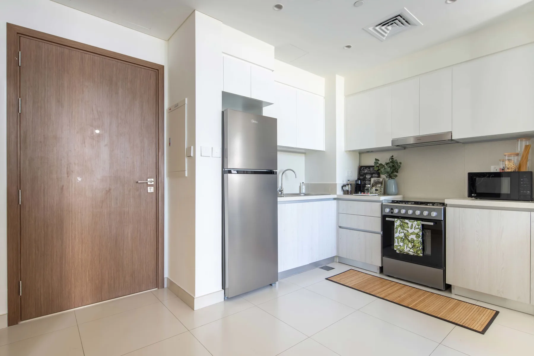 Una cocina luminosa con gabinetes blancos, un refrigerador y una estufa.