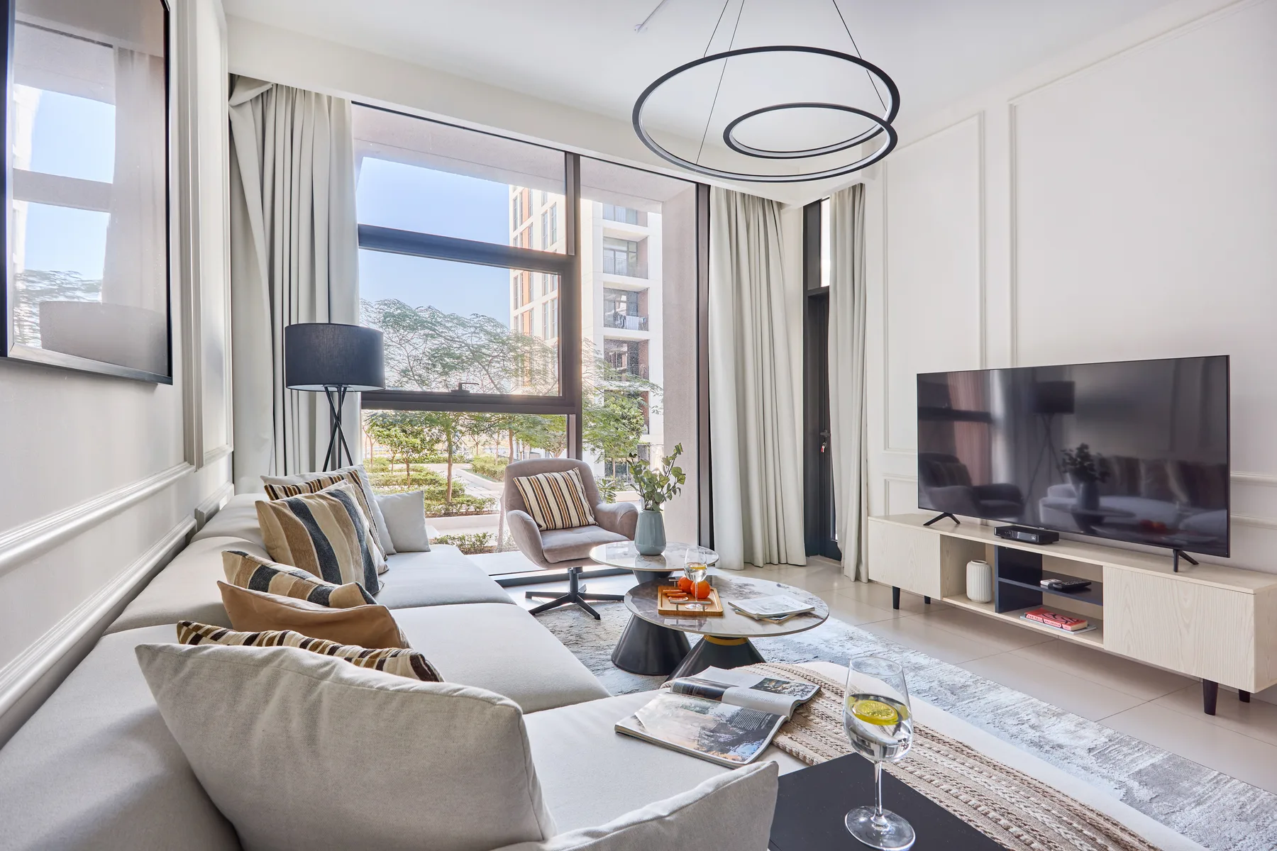 Una sala luminosa con asientos, un televisor y ventanales.
