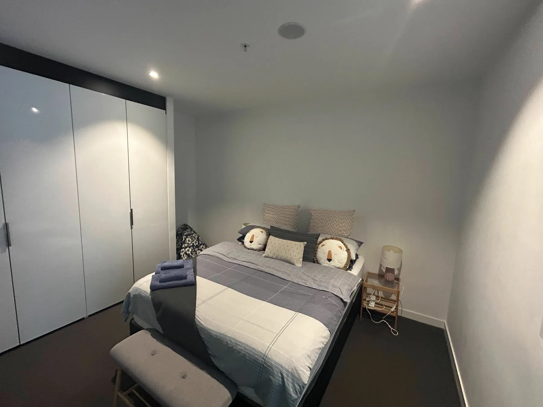 A bedroom with a double bed, wardrobes, and a small bedside table.
