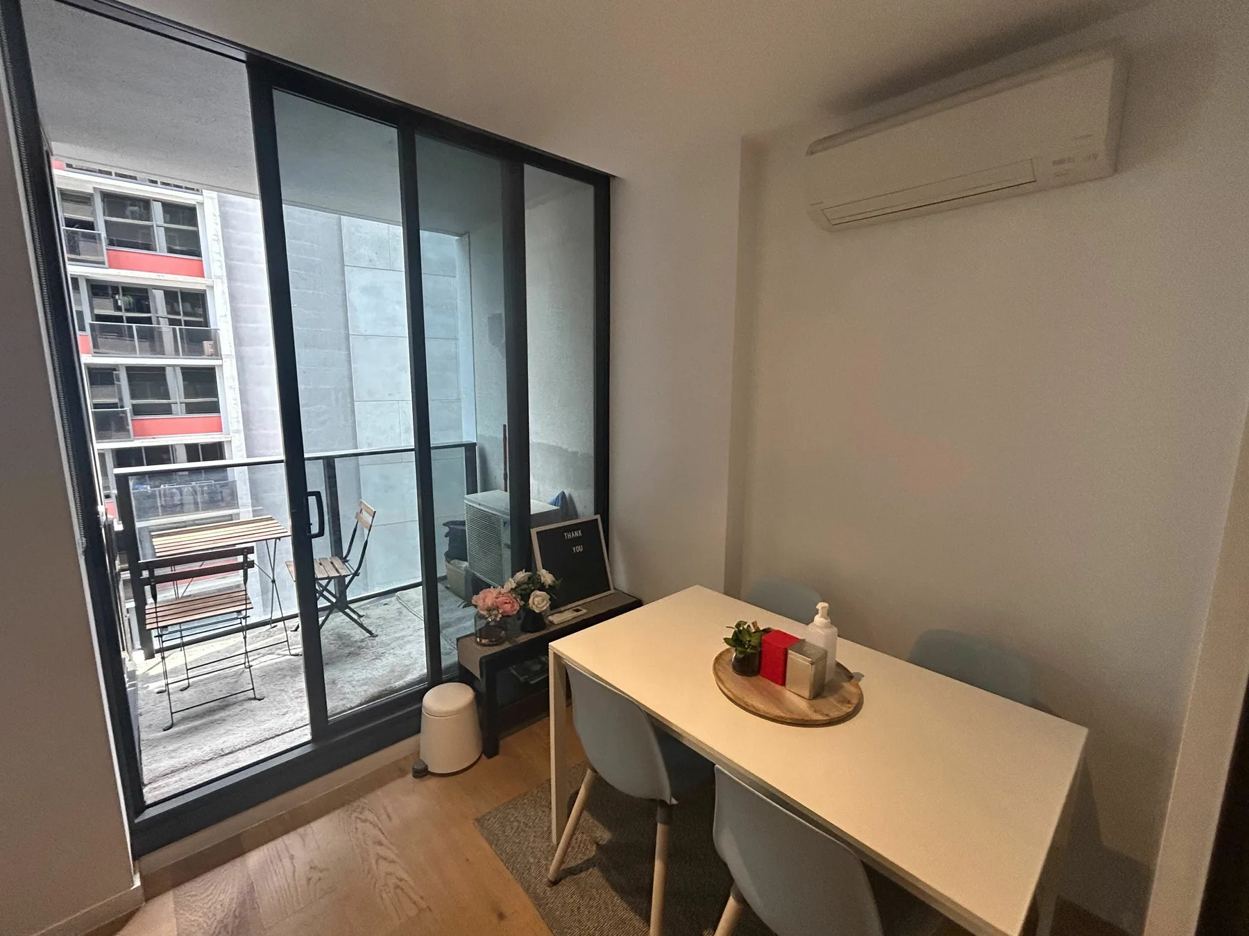 A dining area with a table beside floor-to-ceiling glass doors opening onto a balcony.