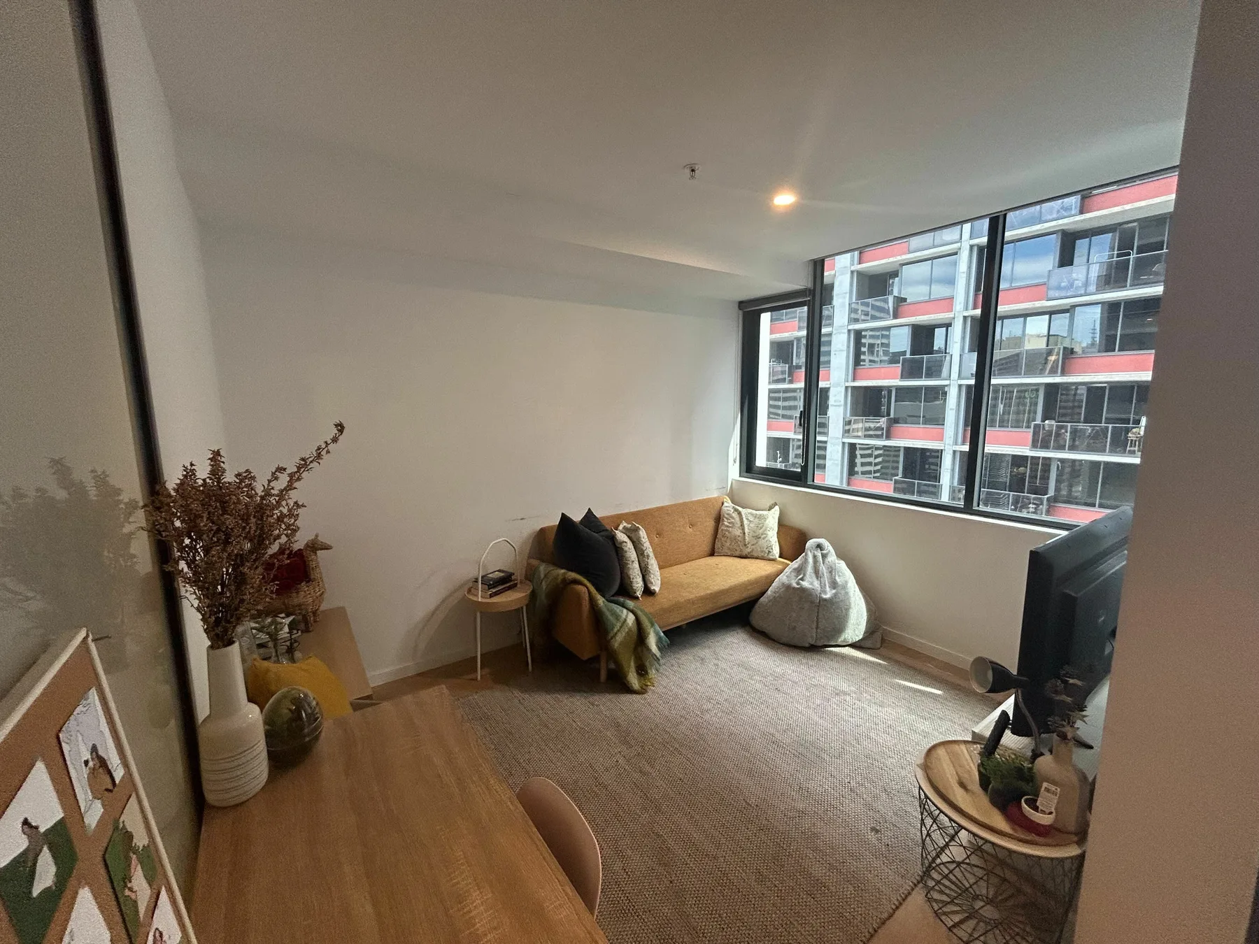 A sitting area with a sofa, rug, and large windows overlooking nearby buildings.