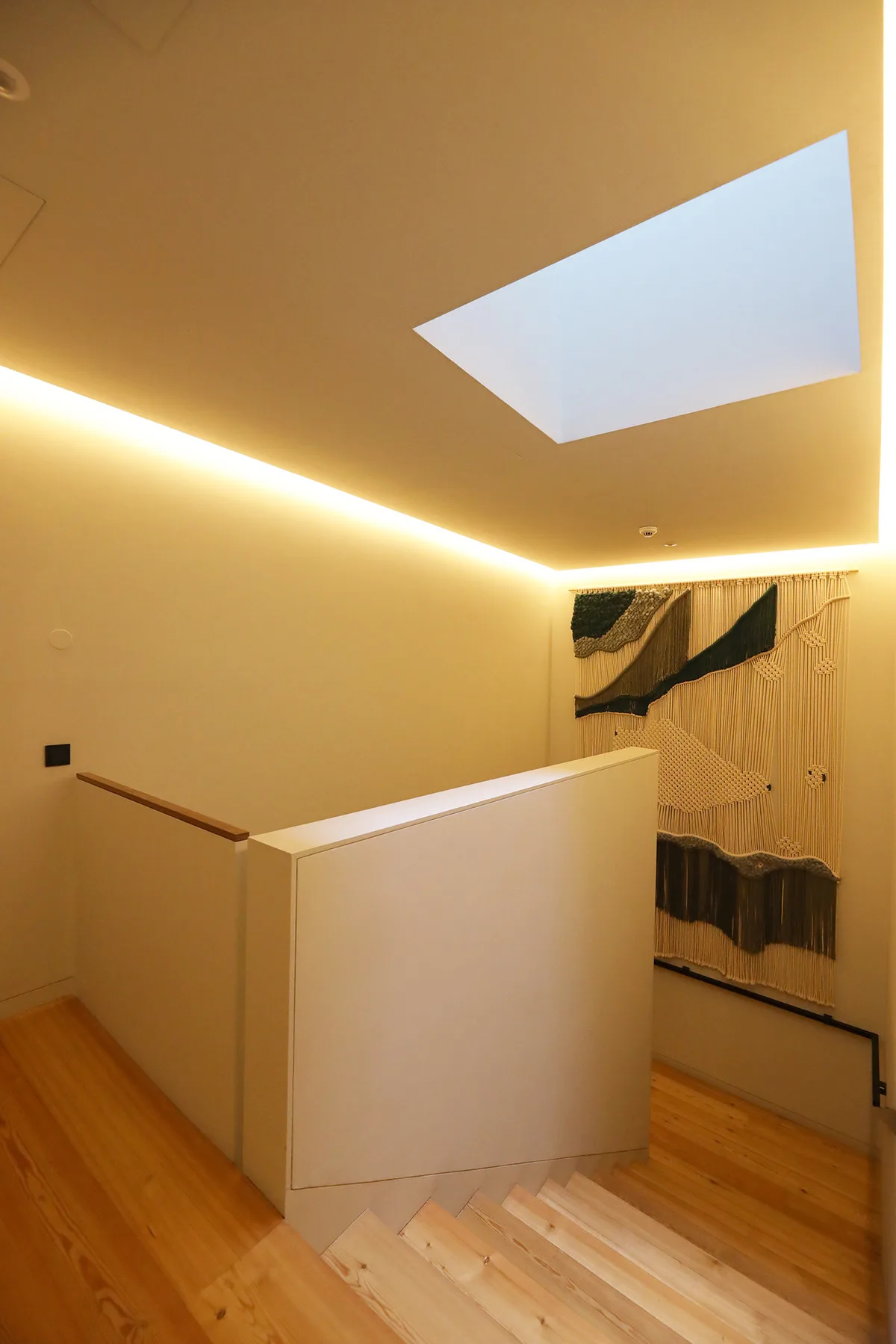 A staircase landing with pale wooden steps and a rectangular ceiling opening.