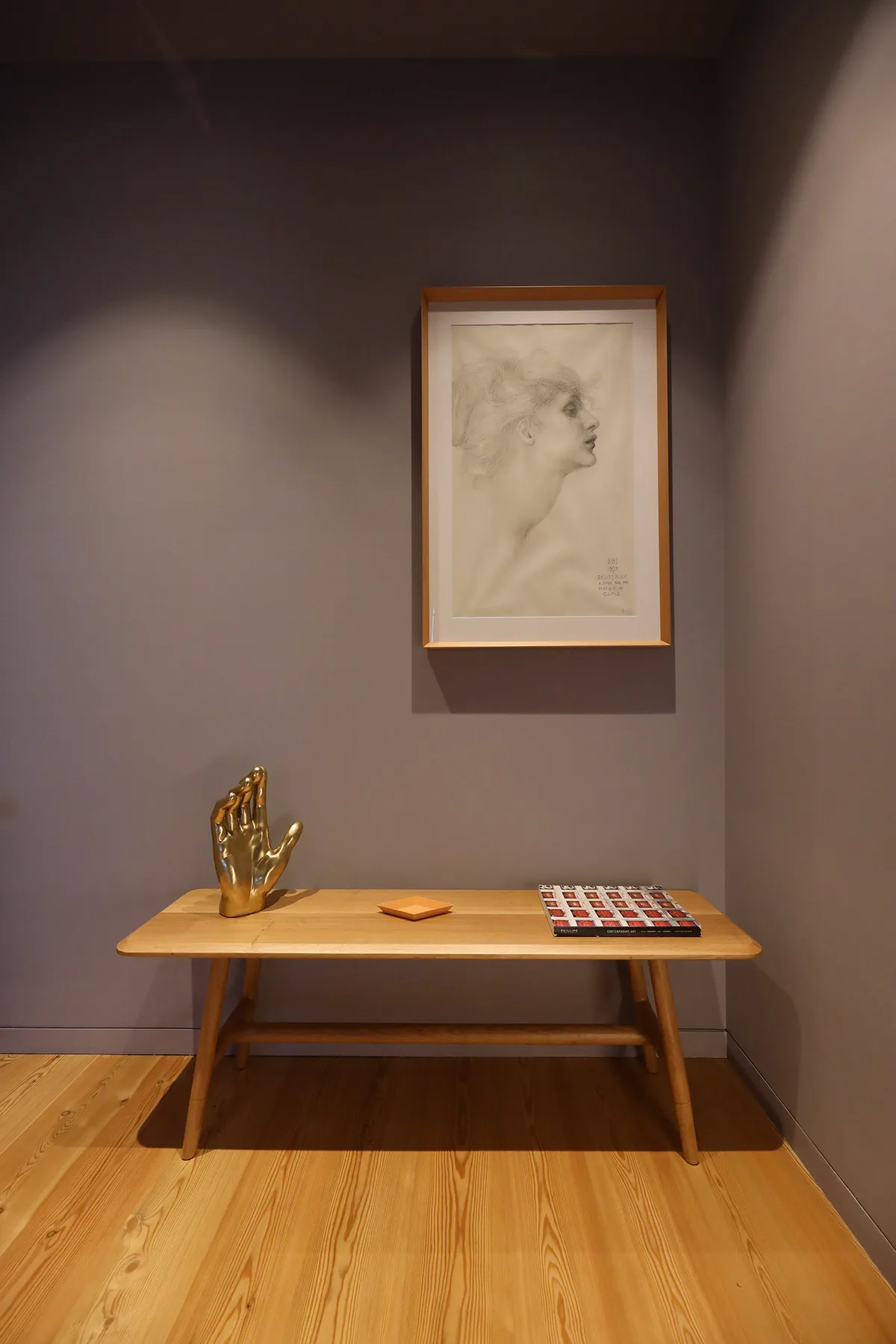 A narrow hallway with a wooden console table and framed artwork on the wall.