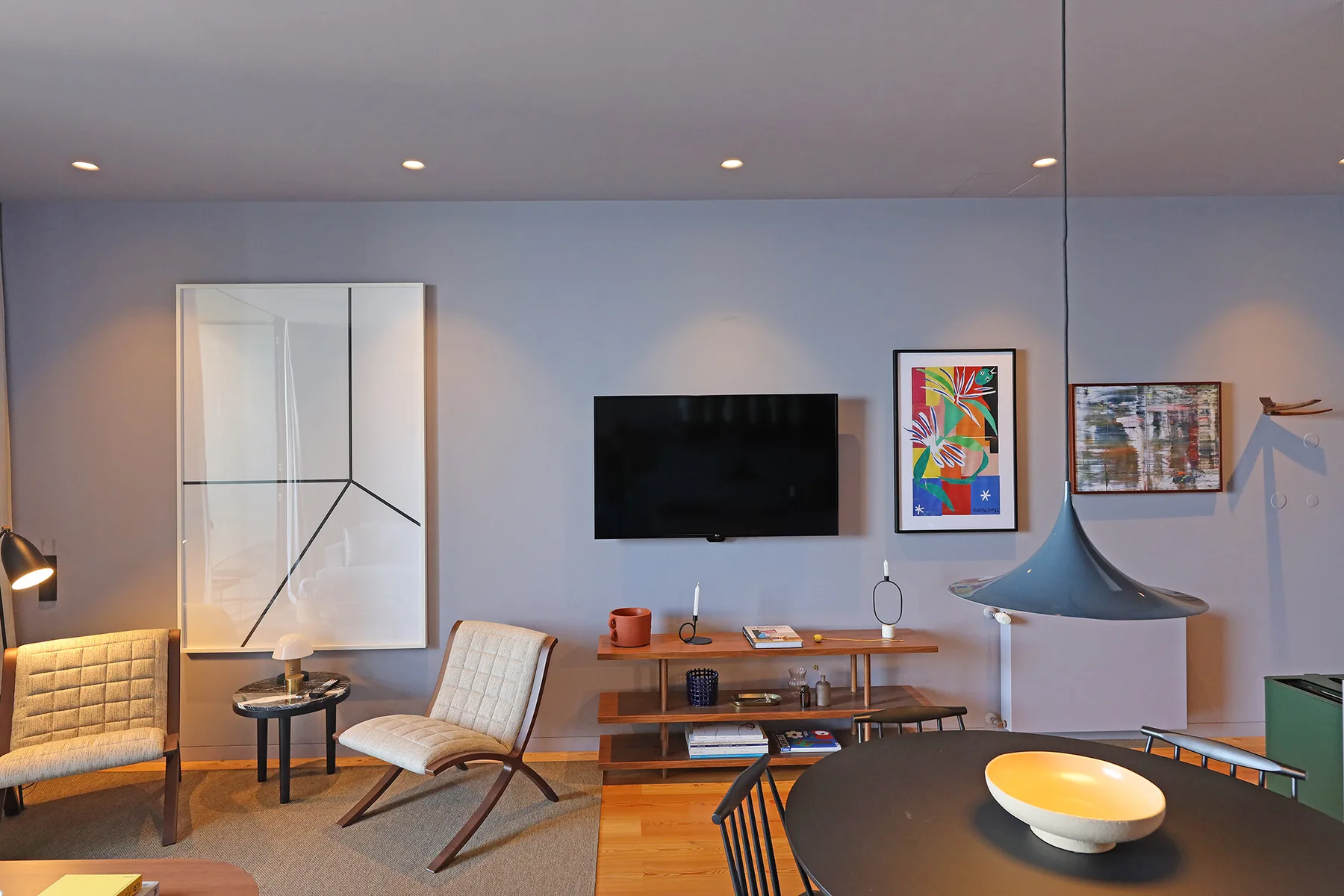 A living room with seating, a television, and colorful wall art.