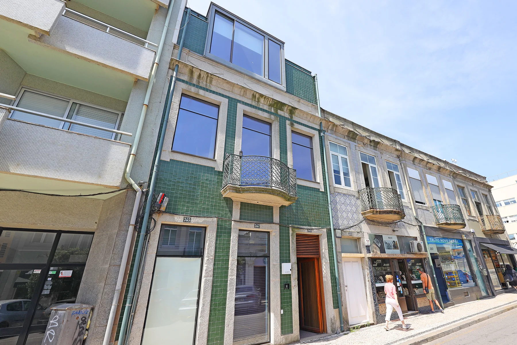 Street-level view of a row of buildings with shops on the ground floor.