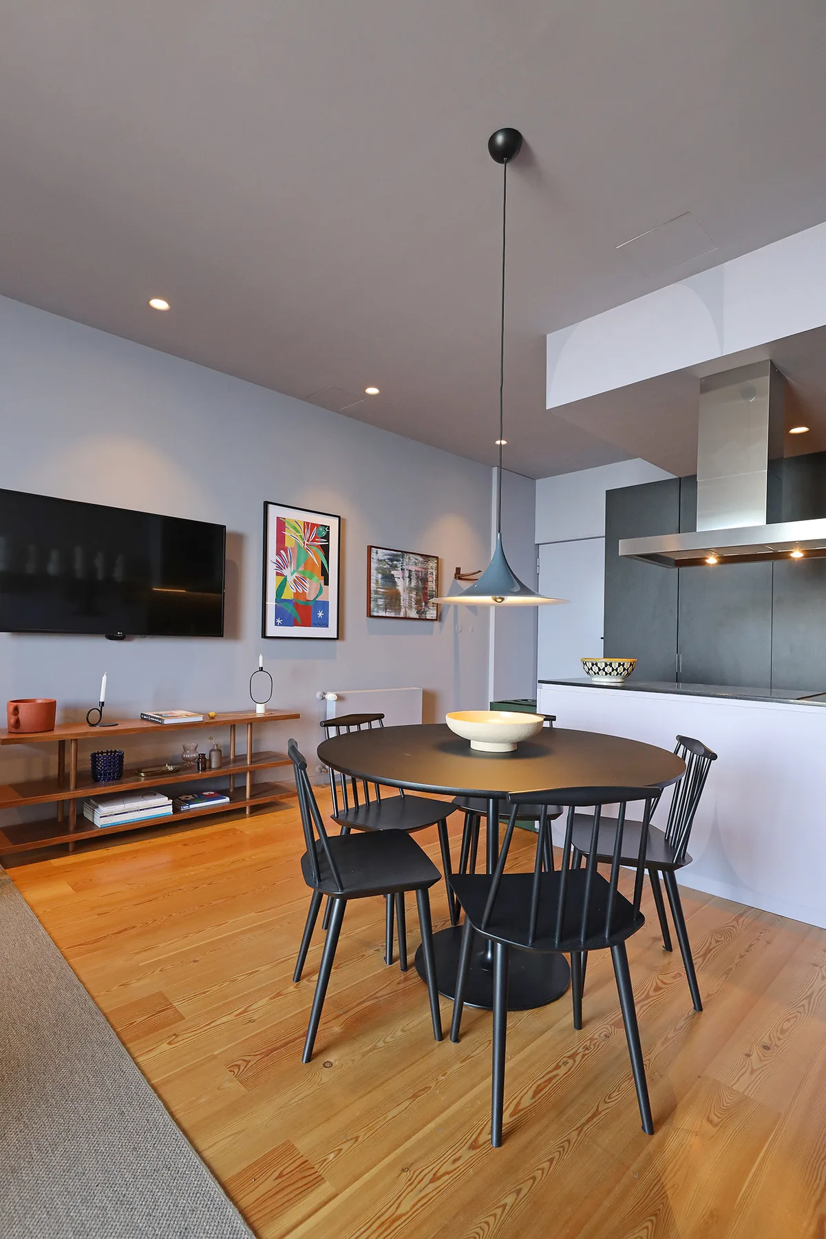A dining area with a round table and black seating beside an open kitchen.