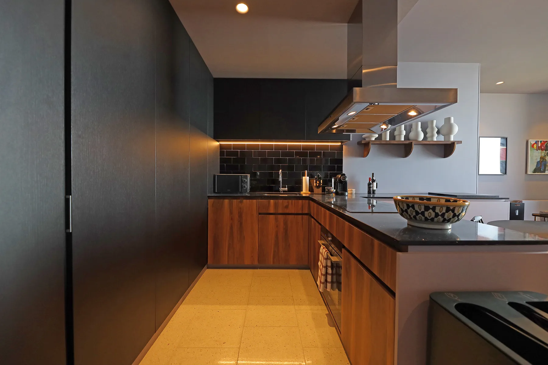 A modern kitchen with dark cabinetry, wooden counters, and a central cooking island.