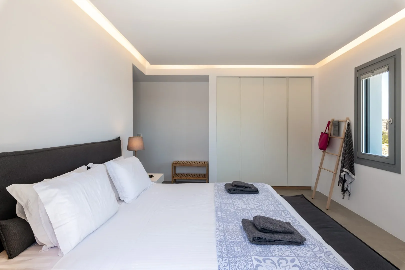 A bright bedroom with a neatly made bed and a window.