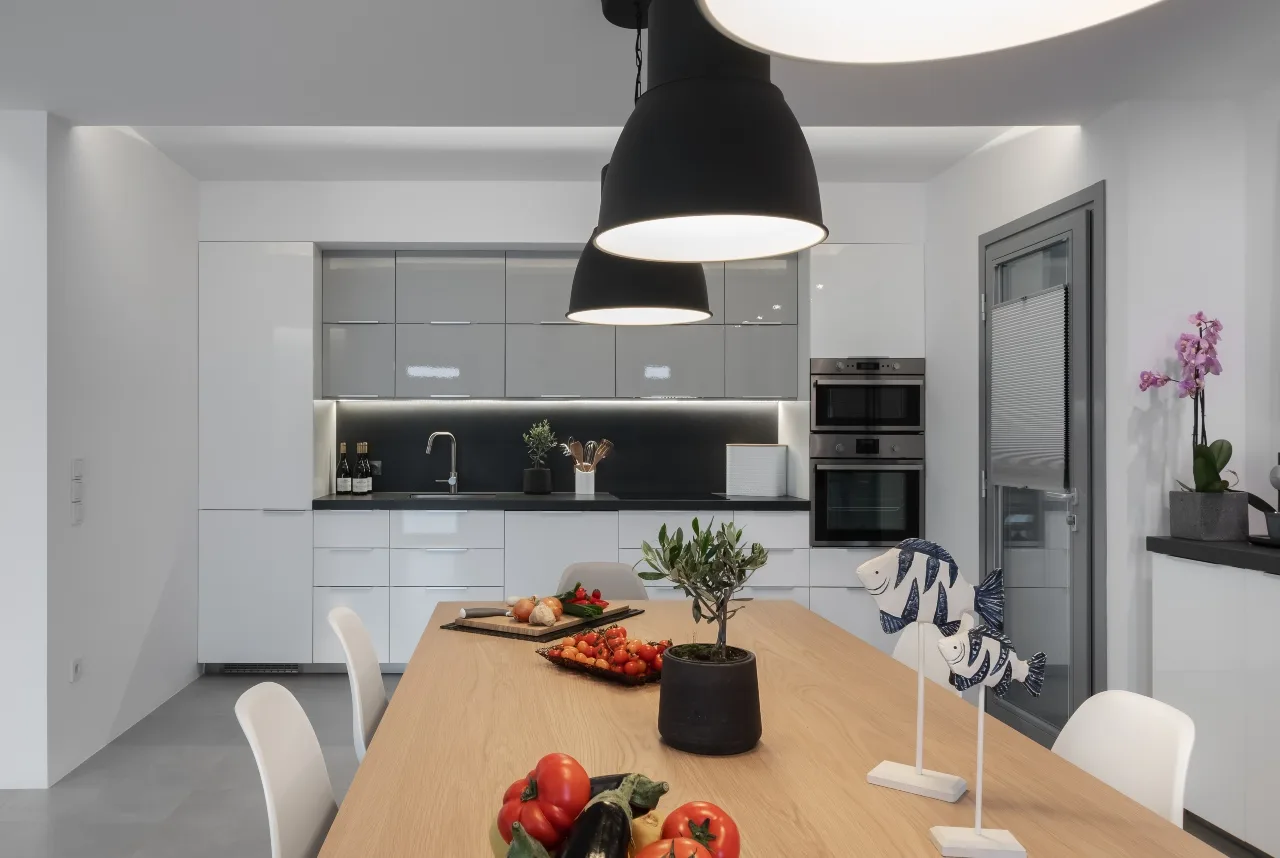 A modern kitchen and dining area with white cabinetry and a wooden table.