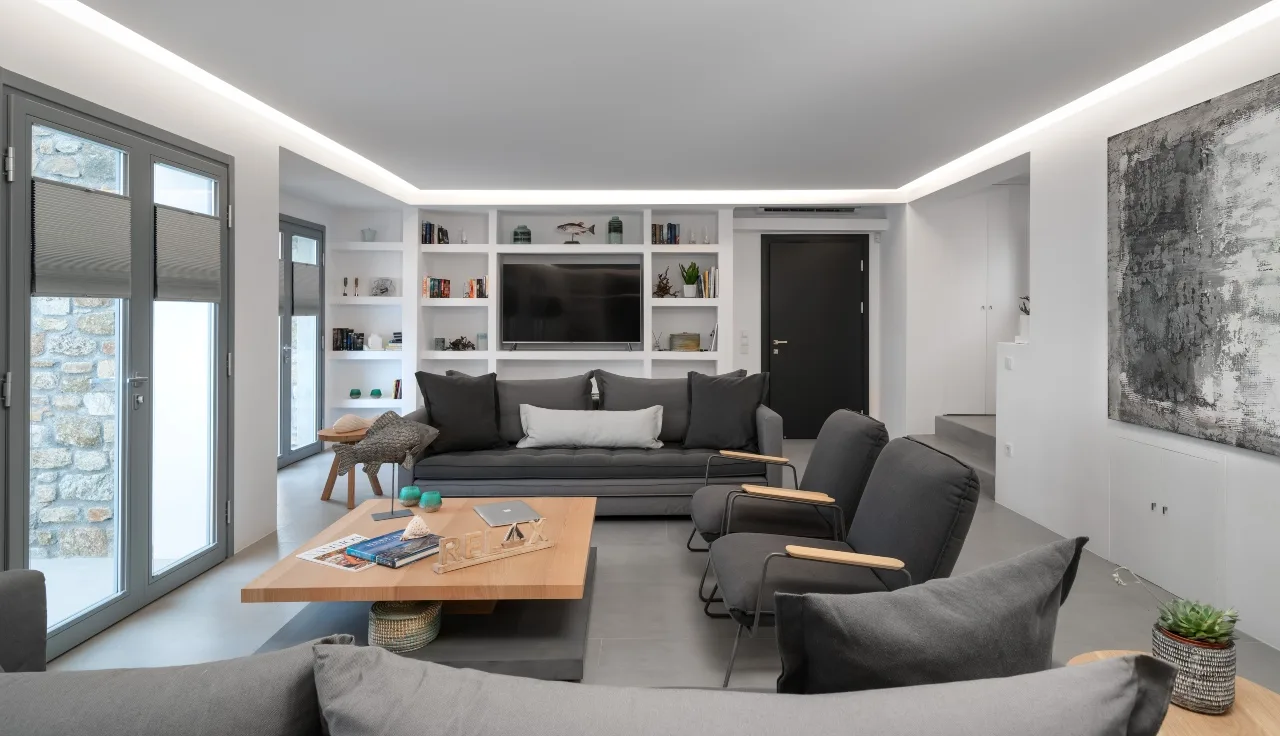 A modern living room with gray seating and built-in shelves.