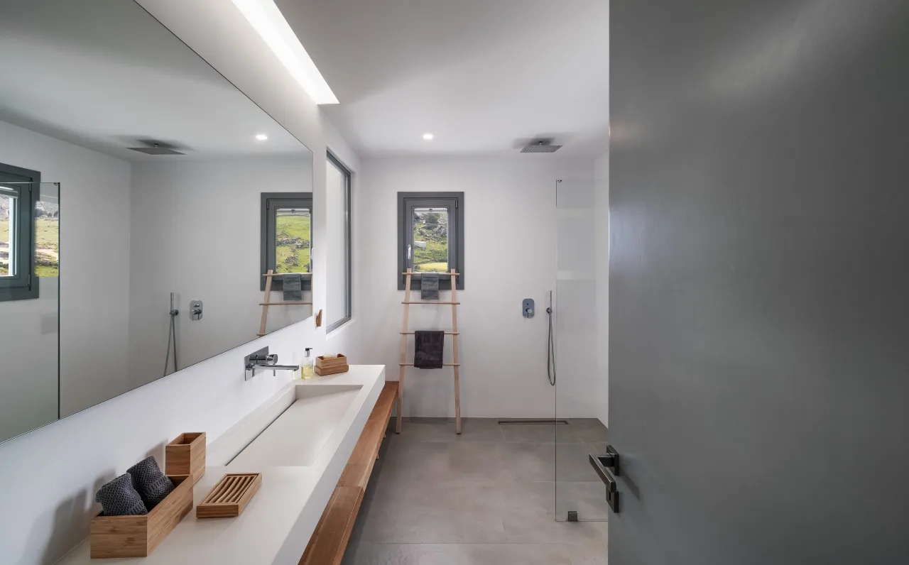 A bright bathroom with a long sink counter and shower.