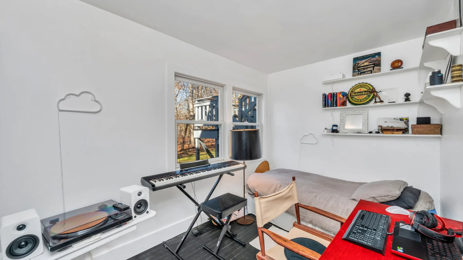 Una habitación luminosa con teclado, altavoces y asientos junto a la ventana.