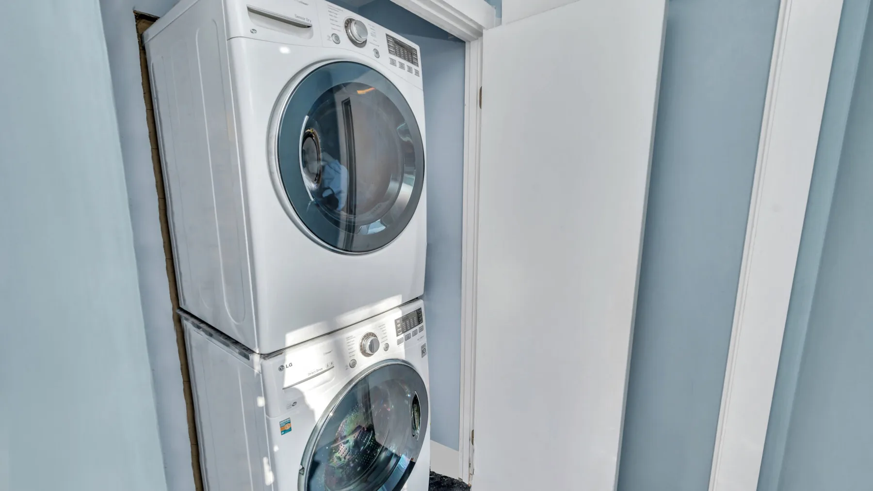 Una zona de lavandería con una lavadora y secadora apiladas en un armario blanco.