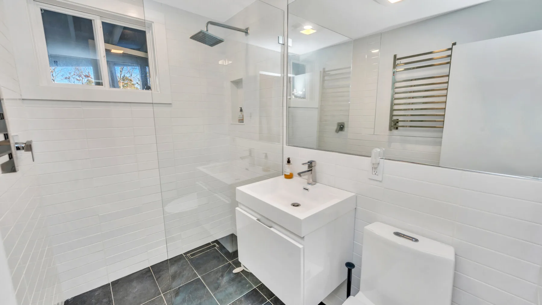 Un baño luminoso con un lavabo debajo de un gran espejo.