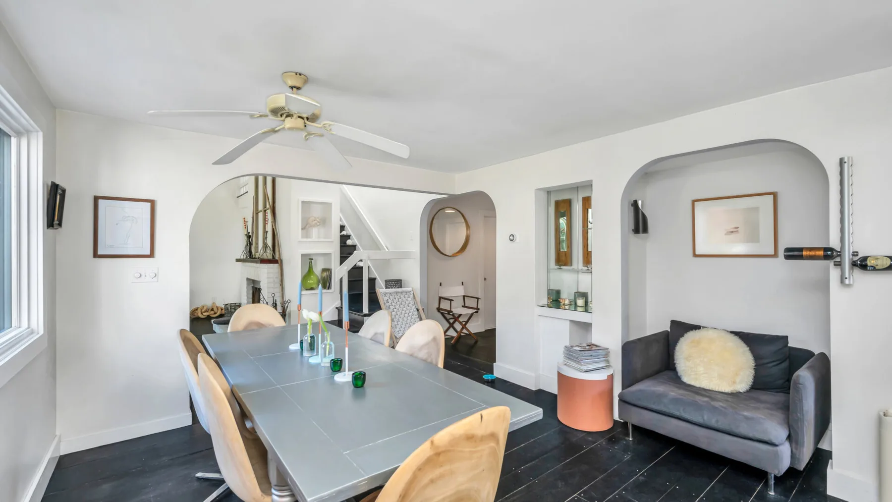 Un comedor luminoso con una mesa larga junto a un arco que da a una sala.