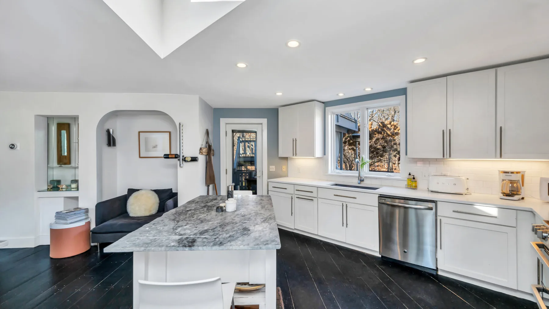 Una cocina moderna y luminosa con gabinetes blancos y una gran isla con cubierta de piedra.