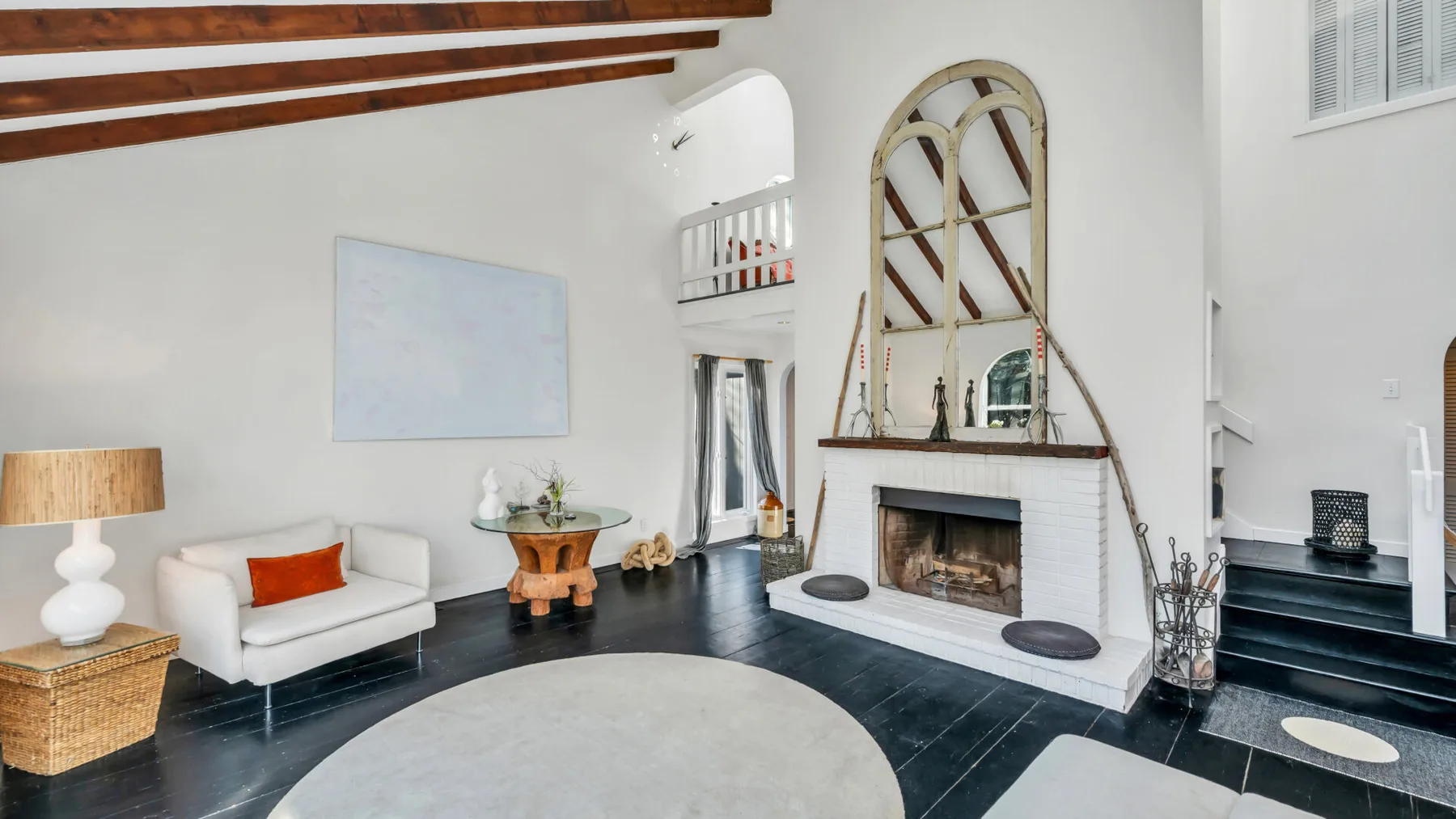 Una sala de estar luminosa con chimenea y asientos alrededor de una alfombra grande.