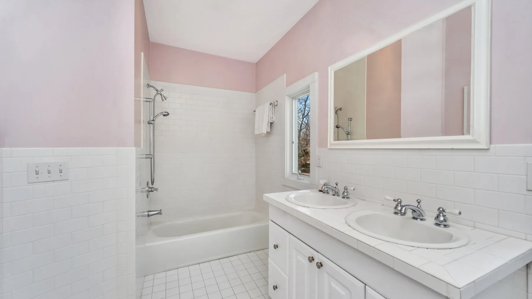 Un baño con bañera, ducha y tocador con dos lavabos.