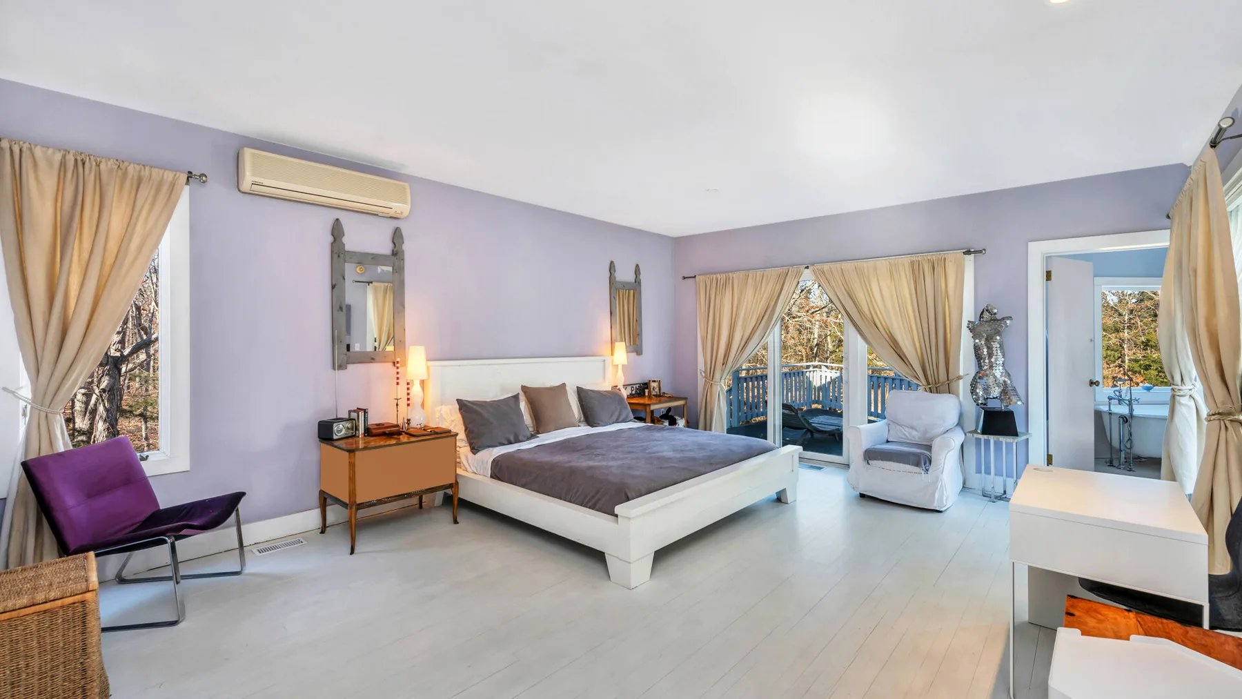 Un dormitorio con una cama y asientos junto a grandes ventanas con cortinas.