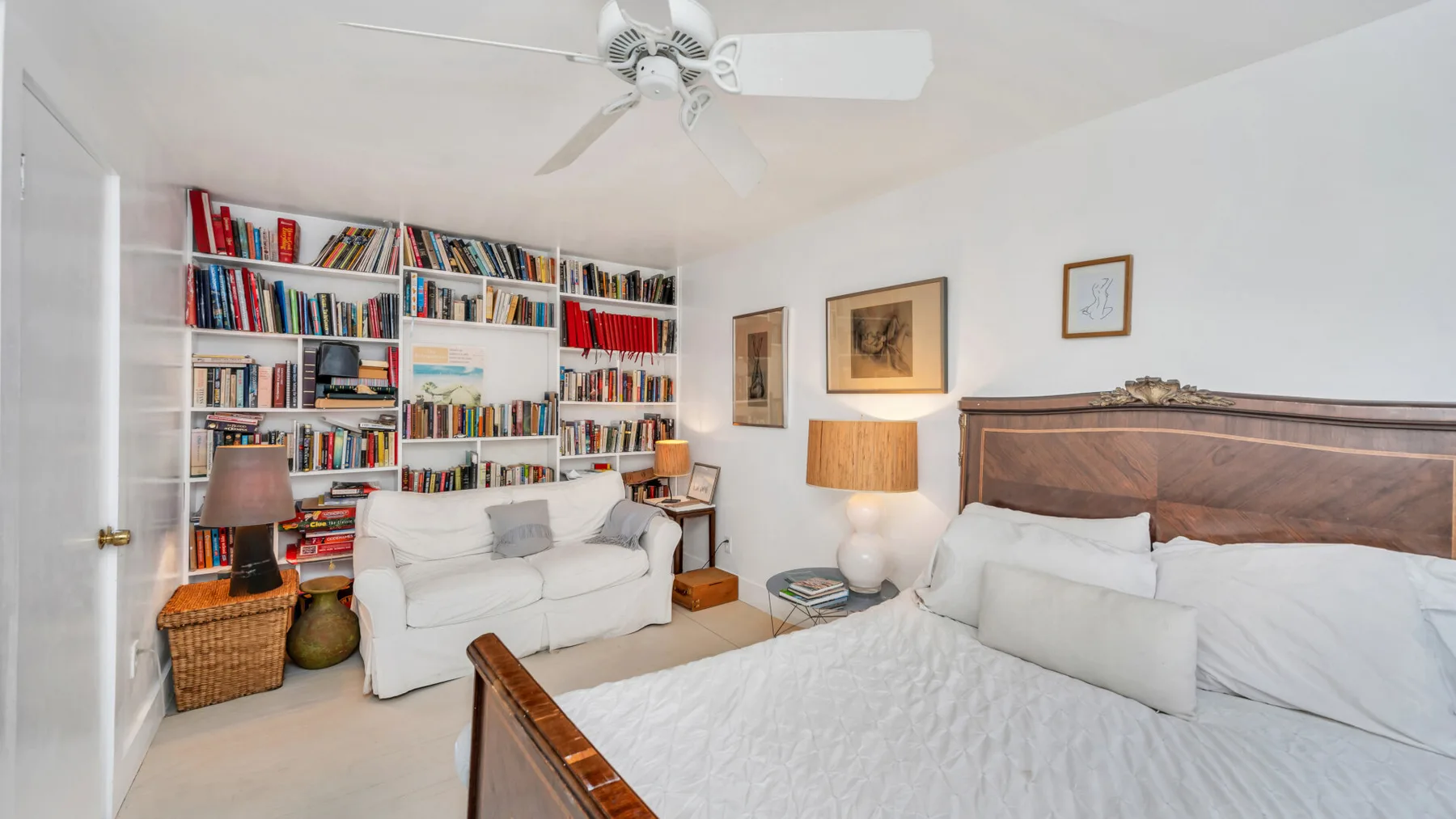 Un dormitorio con una cama grande, una zona de estar y estanterías junto a la pared.