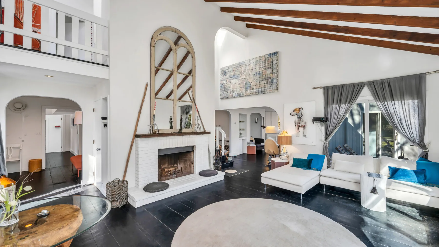 Una sala luminosa con asientos blancos, una chimenea y vigas de madera expuestas.