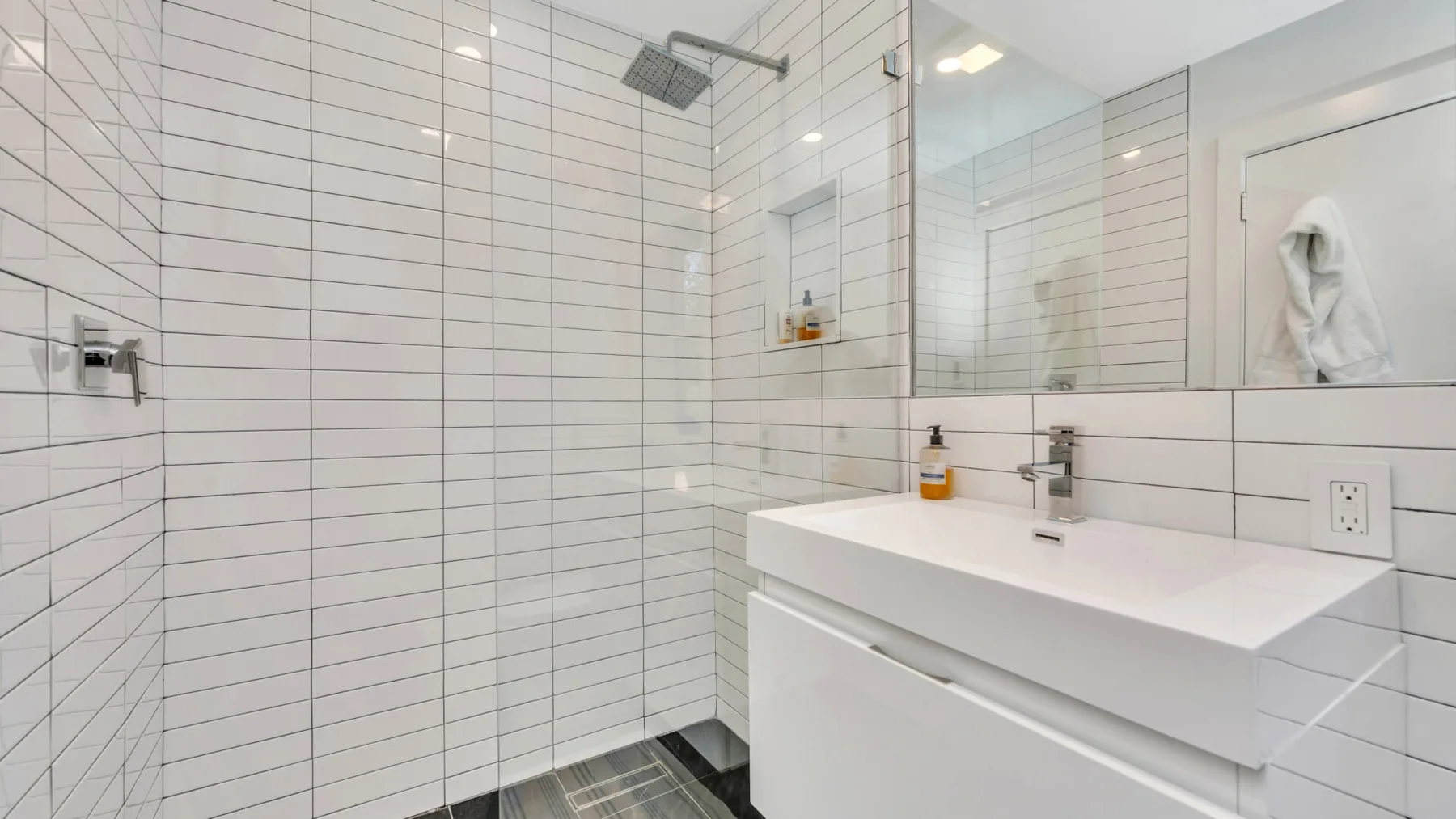Un baño alicatado con un lavabo amplio, espejo y ducha superior.