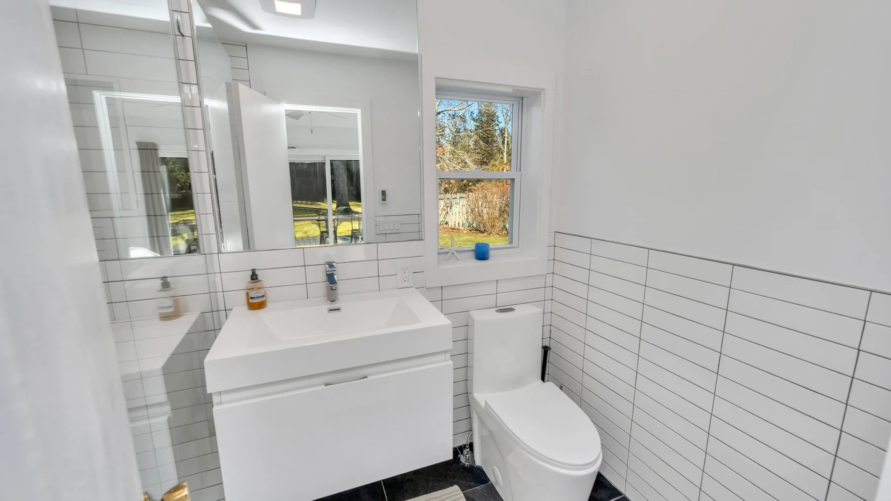 Un baño luminoso con un lavabo blanco, espejo e inodoro.
