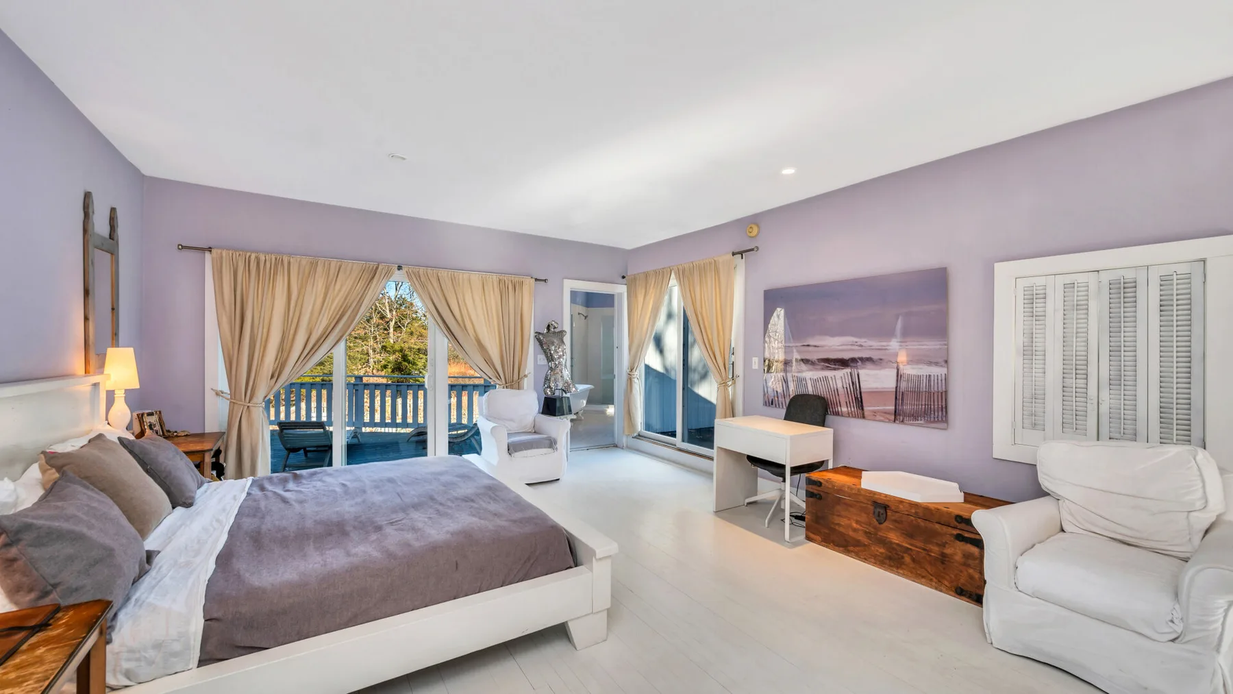 Un dormitorio con una cama grande, asientos y ventanas con vistas a un balcón.