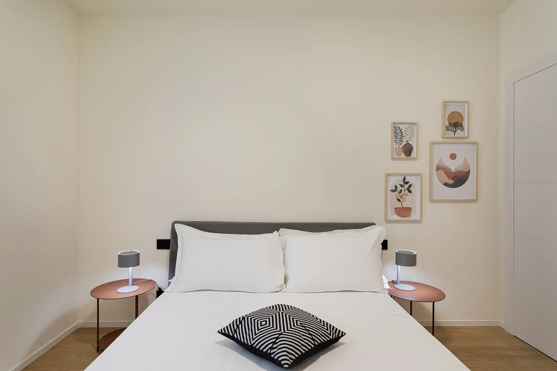 A bedroom with a neatly made bed and framed artwork on the wall.