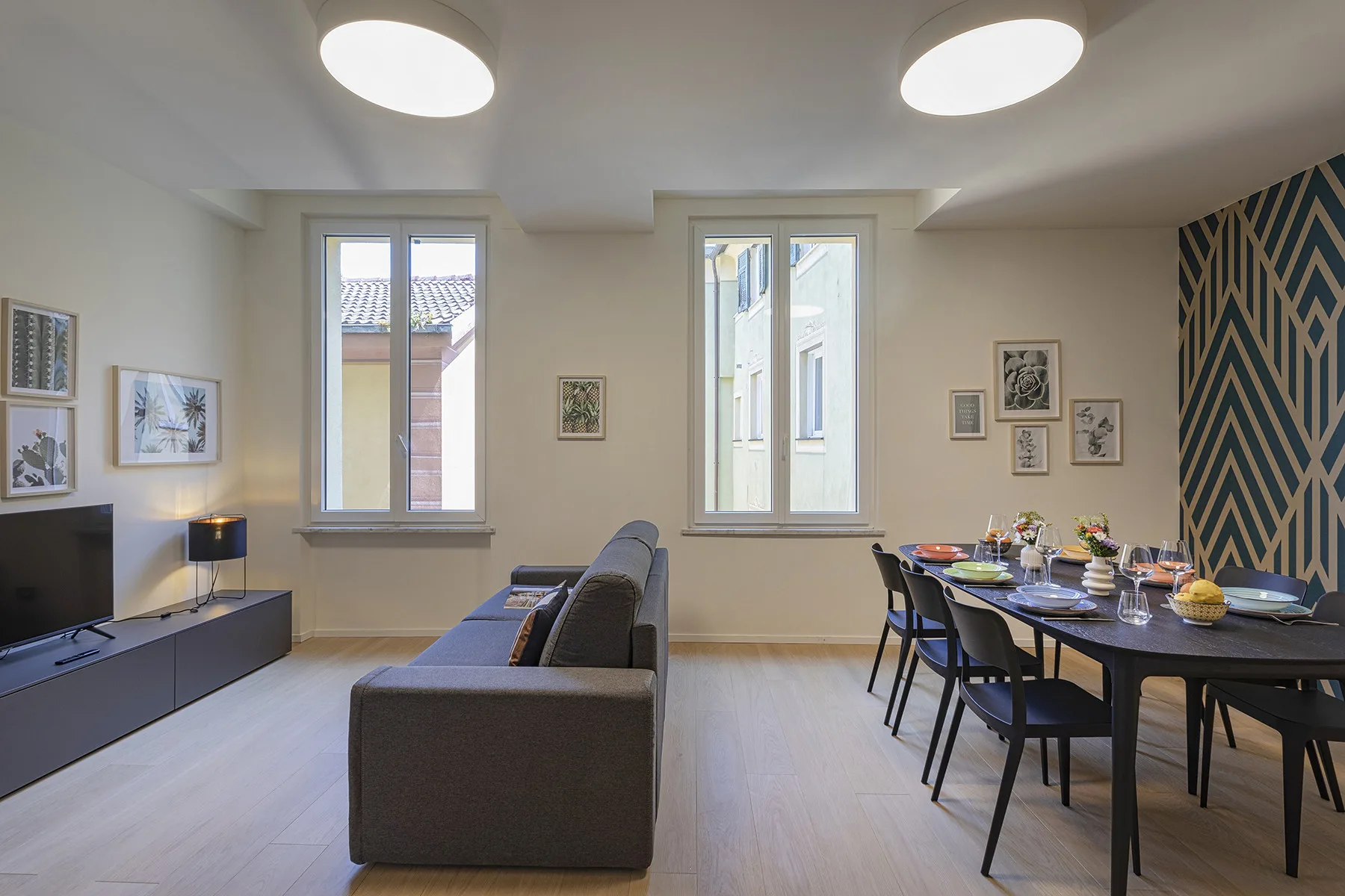 A living and dining area with a sofa, dining table, and patterned accent wall.