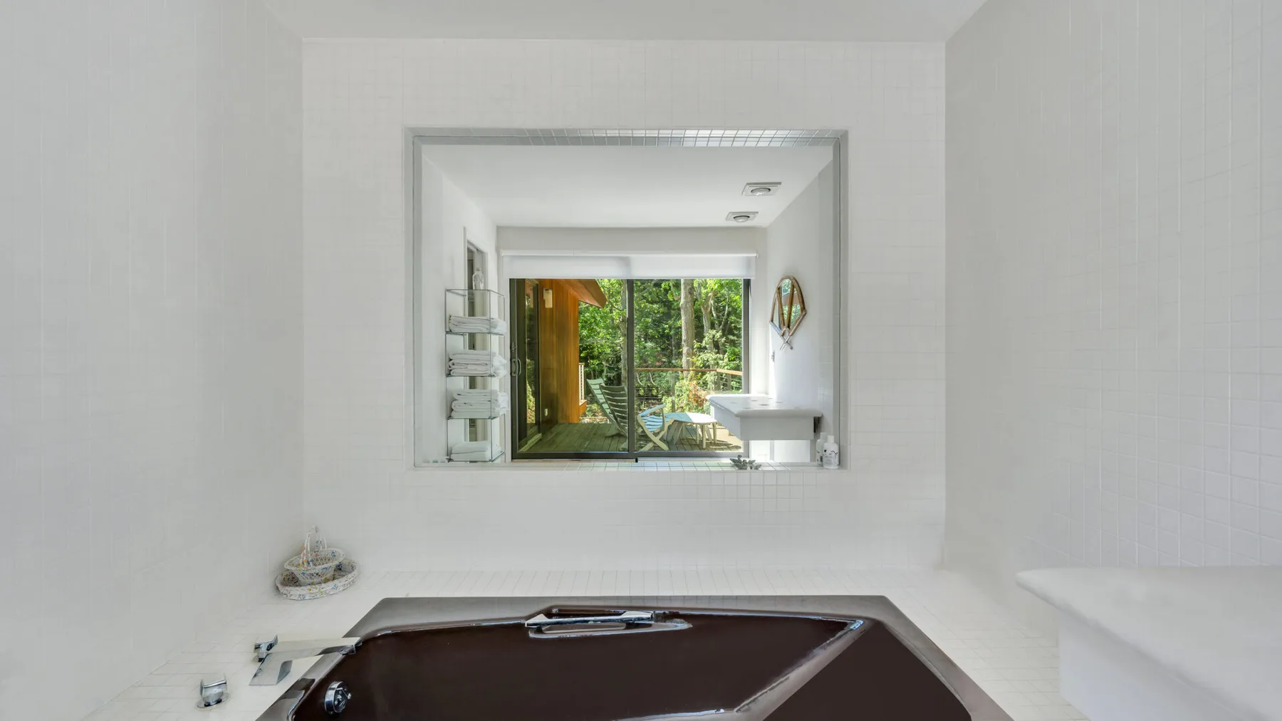 Un baño con una bañera grande y una ventana con vista a la vegetación.