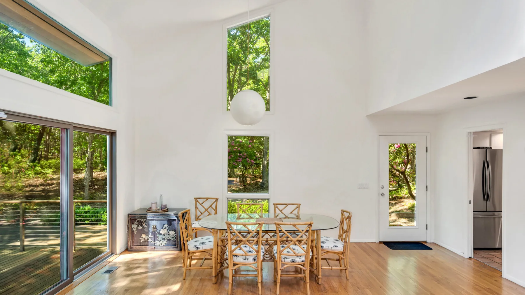 Un comedor luminoso con una mesa de madera y grandes ventanas con vista a la vegetación.
