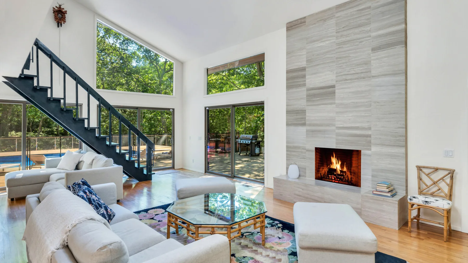 Una sala luminosa con grandes ventanales, una mesa de centro de vidrio y una chimenea.